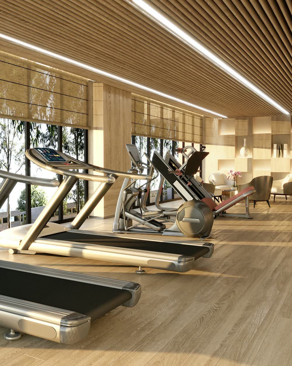 A gym with treadmills by tall windows